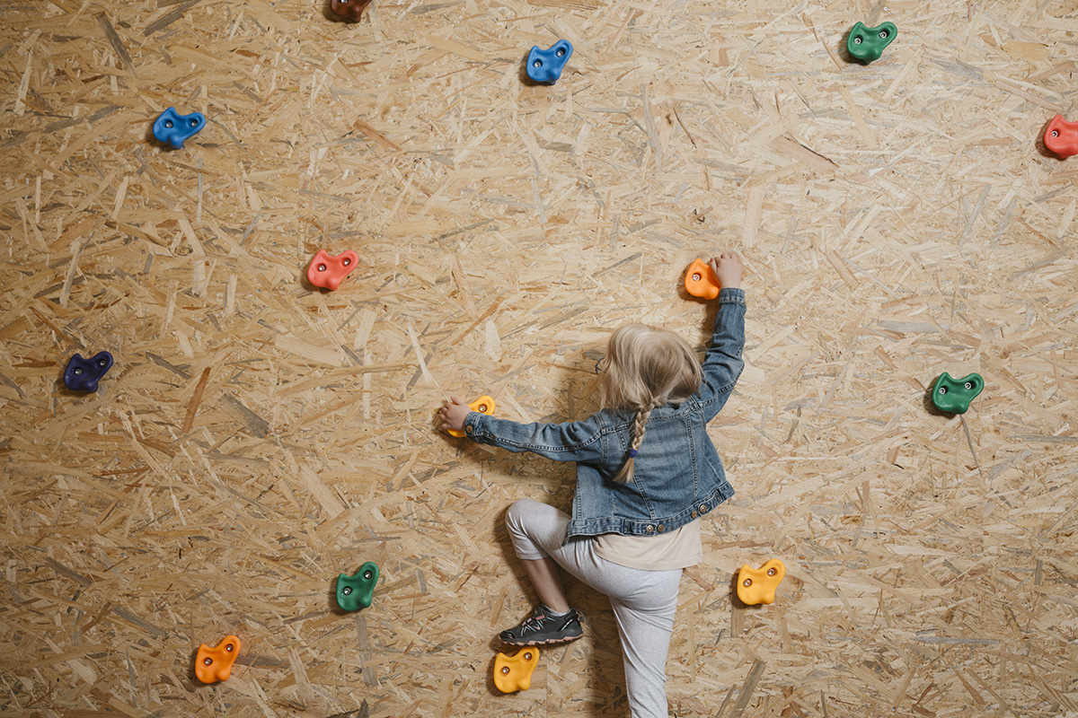 Mädchen klettert an der Indoor-Kletterwand hoch