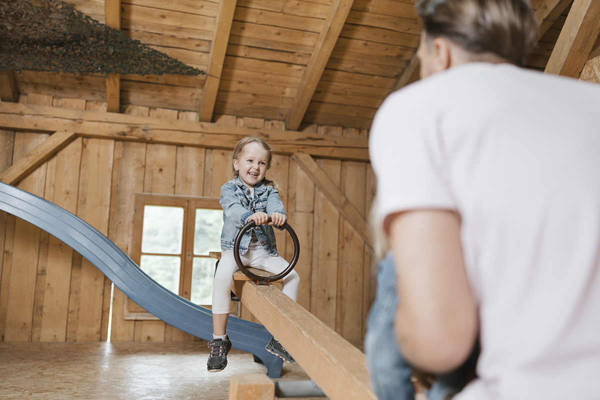 Kind wippt mit Vater auf der Wippe im Innenbereich