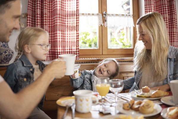Familie mit zwei Kindern sitzt an einem gedeckten Frühstückstisch