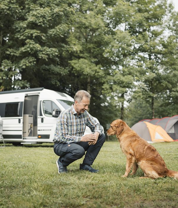Mann mit braunem Hund auf dem Campingplatz